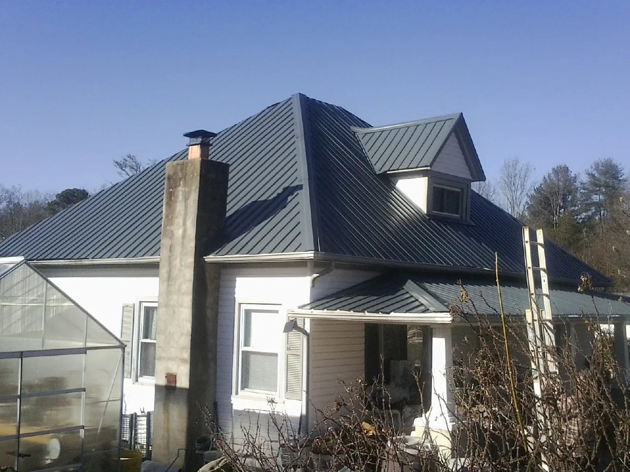 Dark blue standing seam metal roof on a white farmhouse with dormer — Slate & Tile Roof Repair by Roofing Brothers in Catharpin