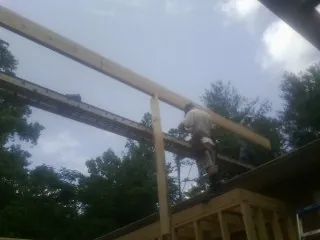 Carpenter setting a ridge beam over a new addition frame — Ice Dam Removal by Roofing Brothers in Catharpin