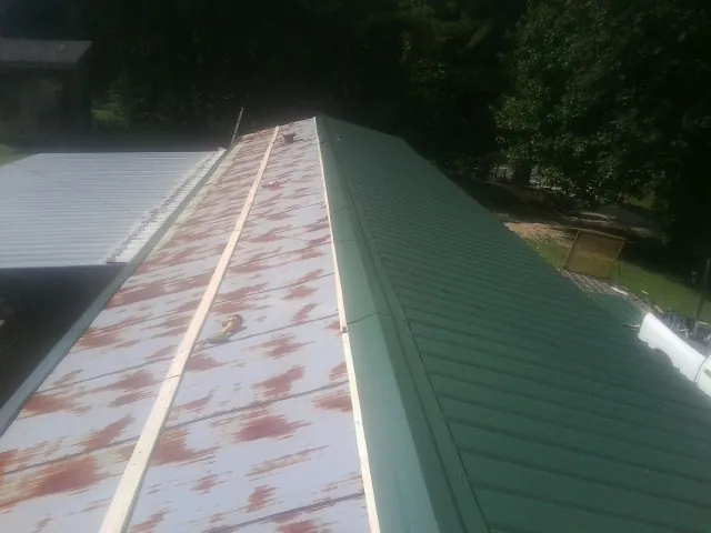 Old rusted panels beside newly installed green metal roofing — Wind Damage Roof Repair by Roofing Brothers in Catharpin