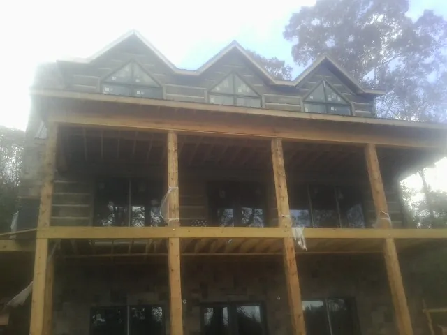 Dormers and porch framing on a large log home under construction — Roof Coating work by our crew in Catharpin
