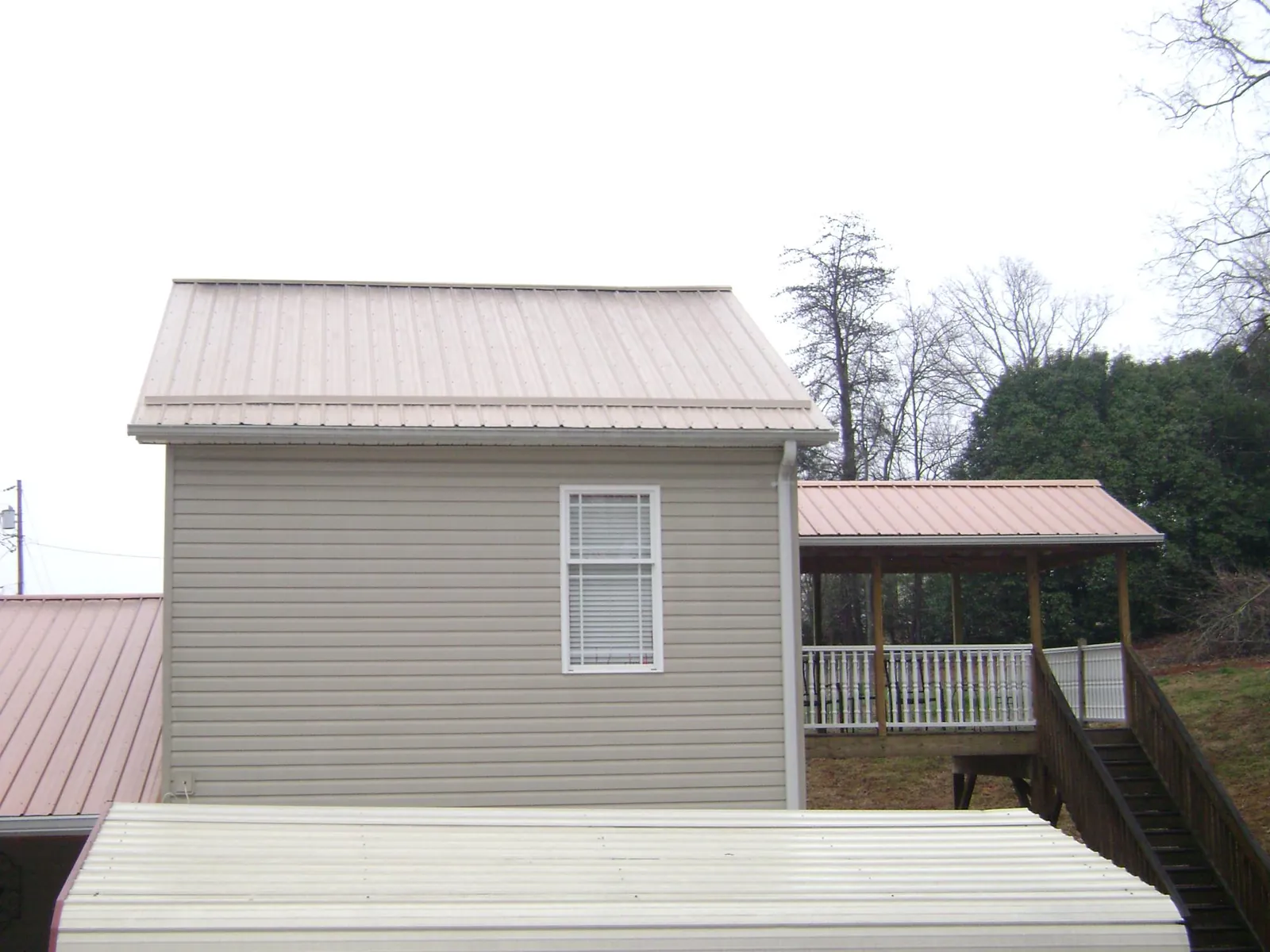 Tan metal roofs on a two story addition and attached porch, from a Roof Replacement job in Catharpin